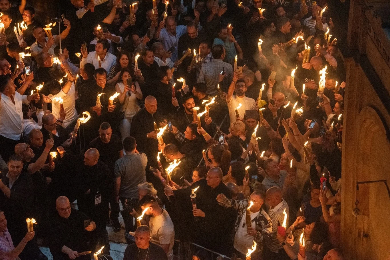 Pelgrims in de Basiliek van het Heilig Graf houden hun kaarsen omhoog nadat het "Heilig Vuur" tot ontbranding kwam in het graf van Jezus op 4 mei 2024, de dag voor de orthodox-christelijke viering van Pasen. Met dank aan: Marinella Bandini/CNA