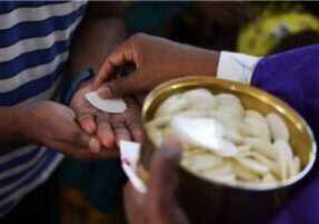Een priester deelt de heilige communie uit./ Noah Seelam/AFP via Getty Images